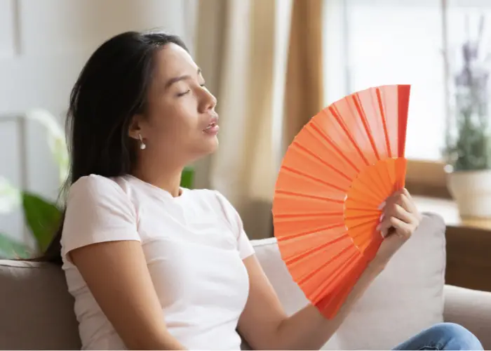 a Filipina lady using her orange fan to cool herself