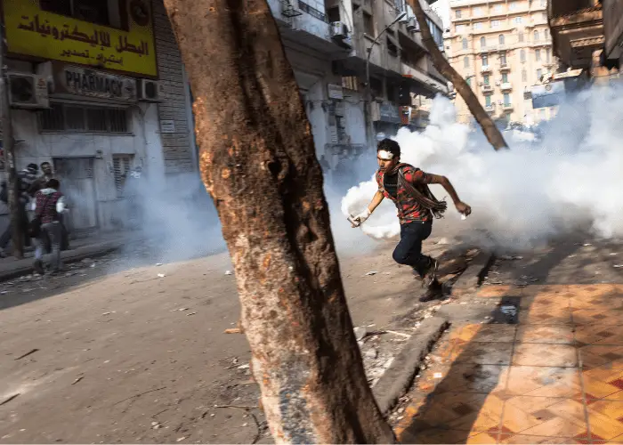  a man holding a tear gas exploded during a riot