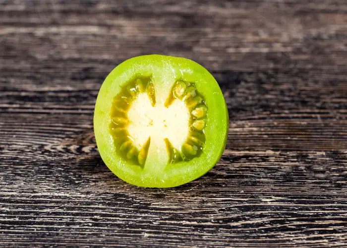 cut green tomato on a wooden chopping board