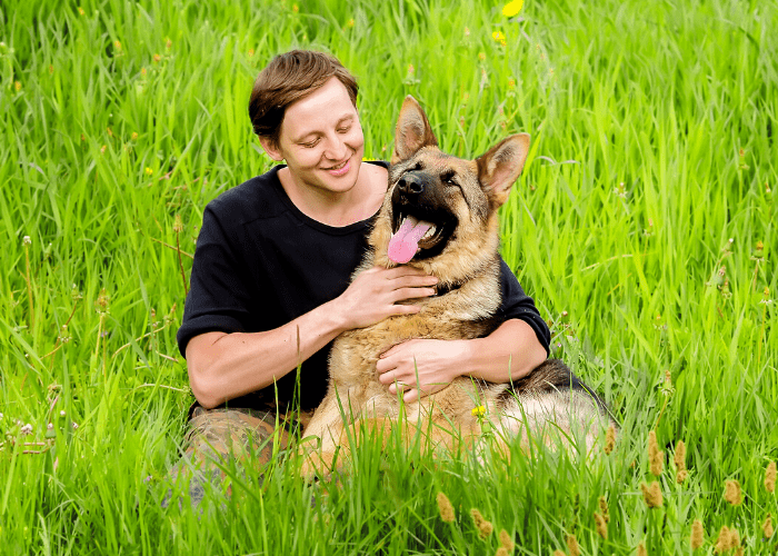 german shepherd and owner in the green grass