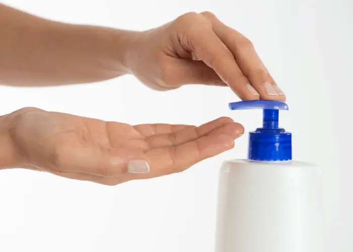 woman hands getting moisturizer from the bottle dispenser